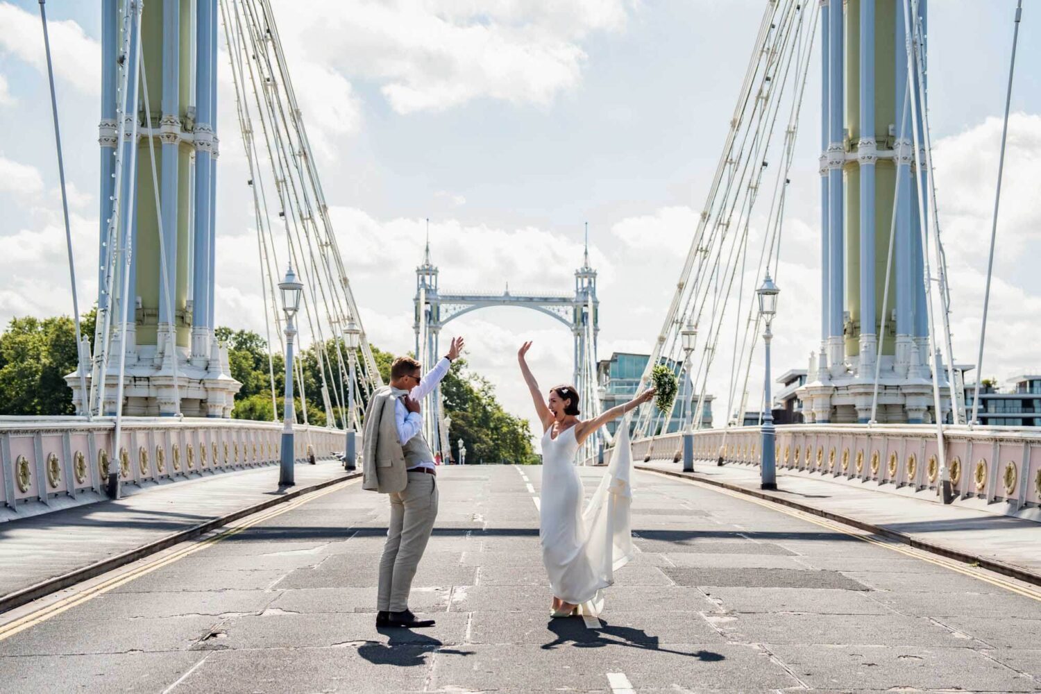 Bride and groom arms up in standing in middle of road on london bridge Chelsea wedding.
