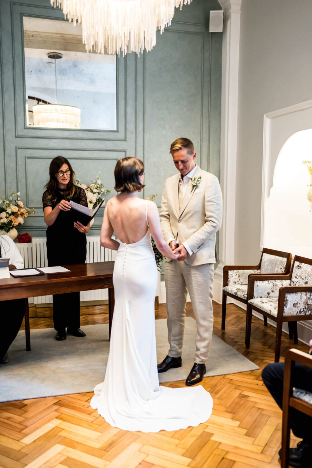 Back of bride holding husband's hand who is looking down Chelsea wedding.