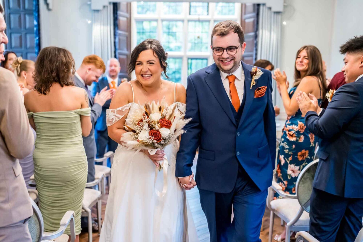 Bride and groom walking back down the aisle smiling at guests Lewes wedding.