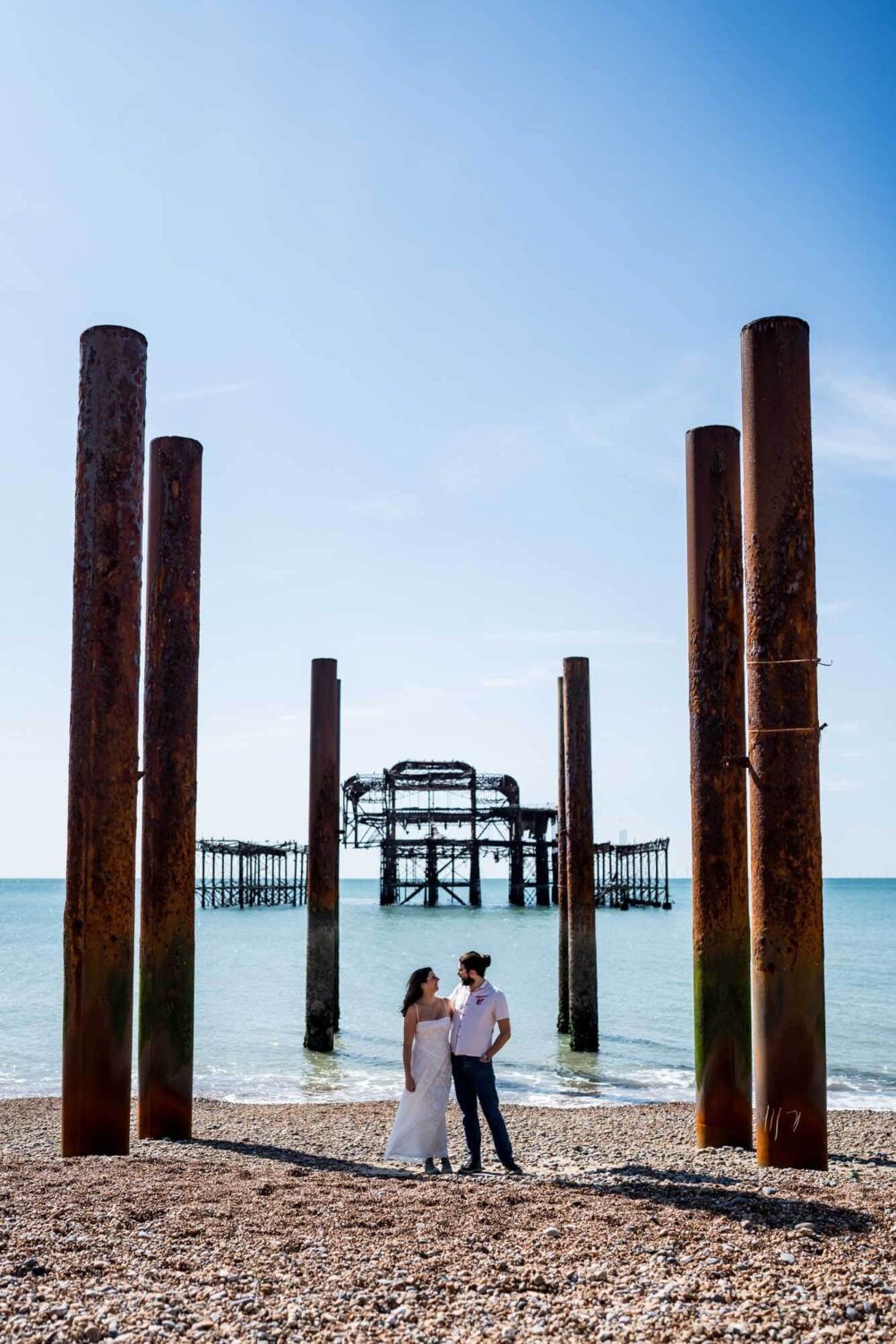 Couple standing along the iconic west pier pillars Brighton wedding.