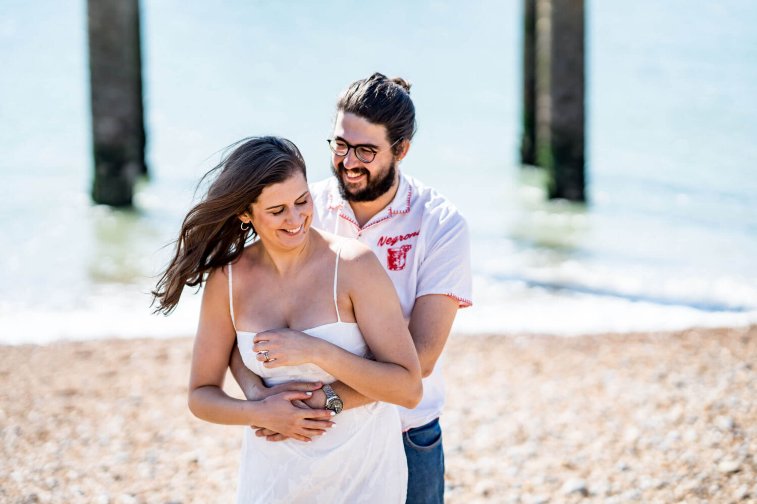 Couple looking down laughing embracing each other Brighton beach Brighton wedding.