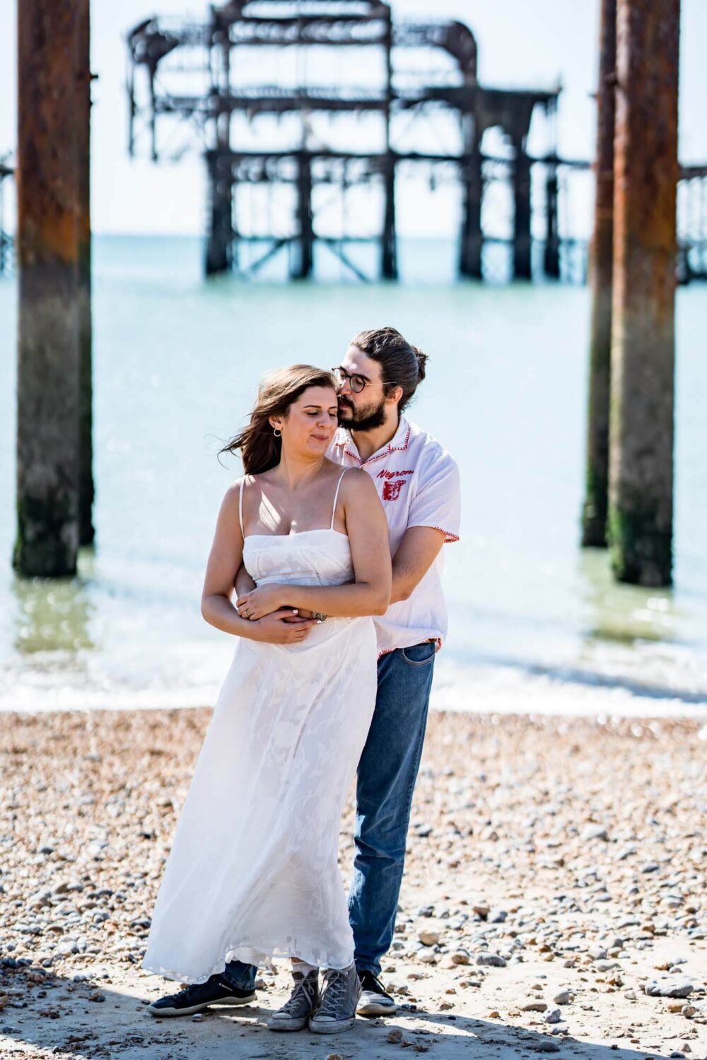 Couple looking down laughing embracing each other Brighton beach Brighton wedding.