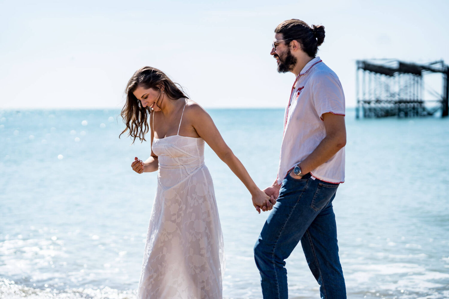 Couple looking down laughing embracing each other Brighton beach Brighton wedding.
