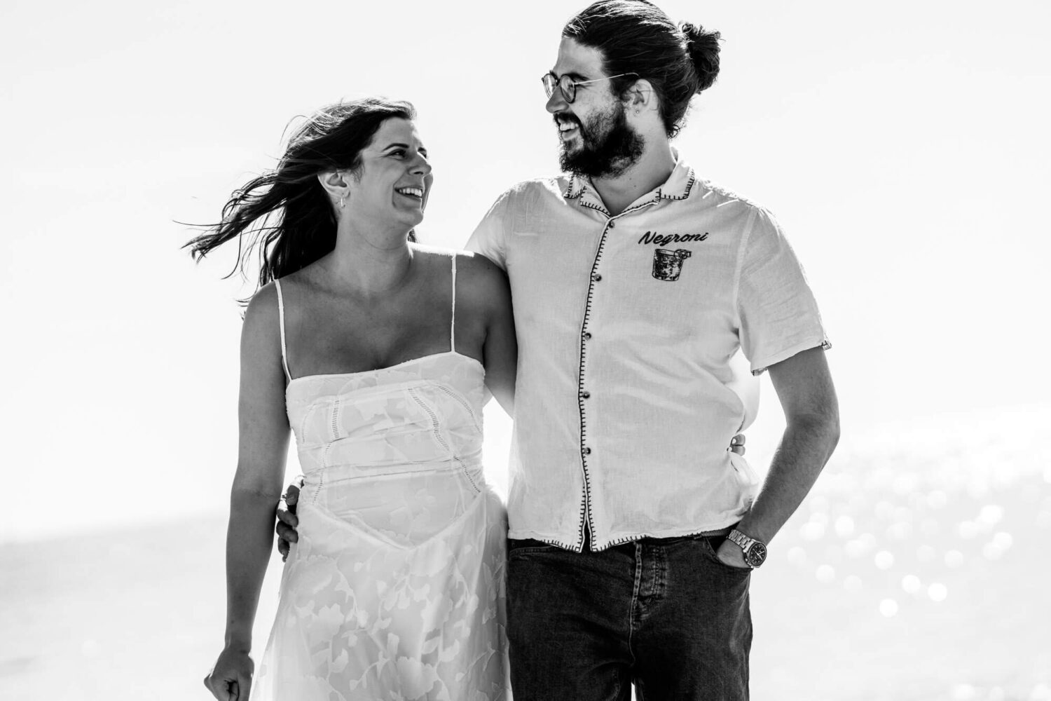 Couple arm in arm smiling laughing looking at each other Brighton wedding.