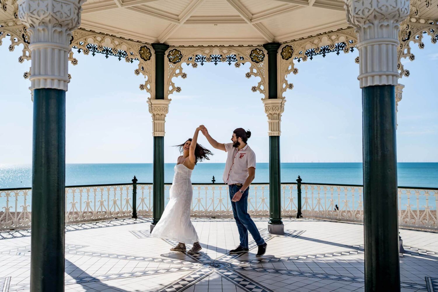 Couple doing a twirl - man and woman - on Brighton bandstand Brighton wedding.