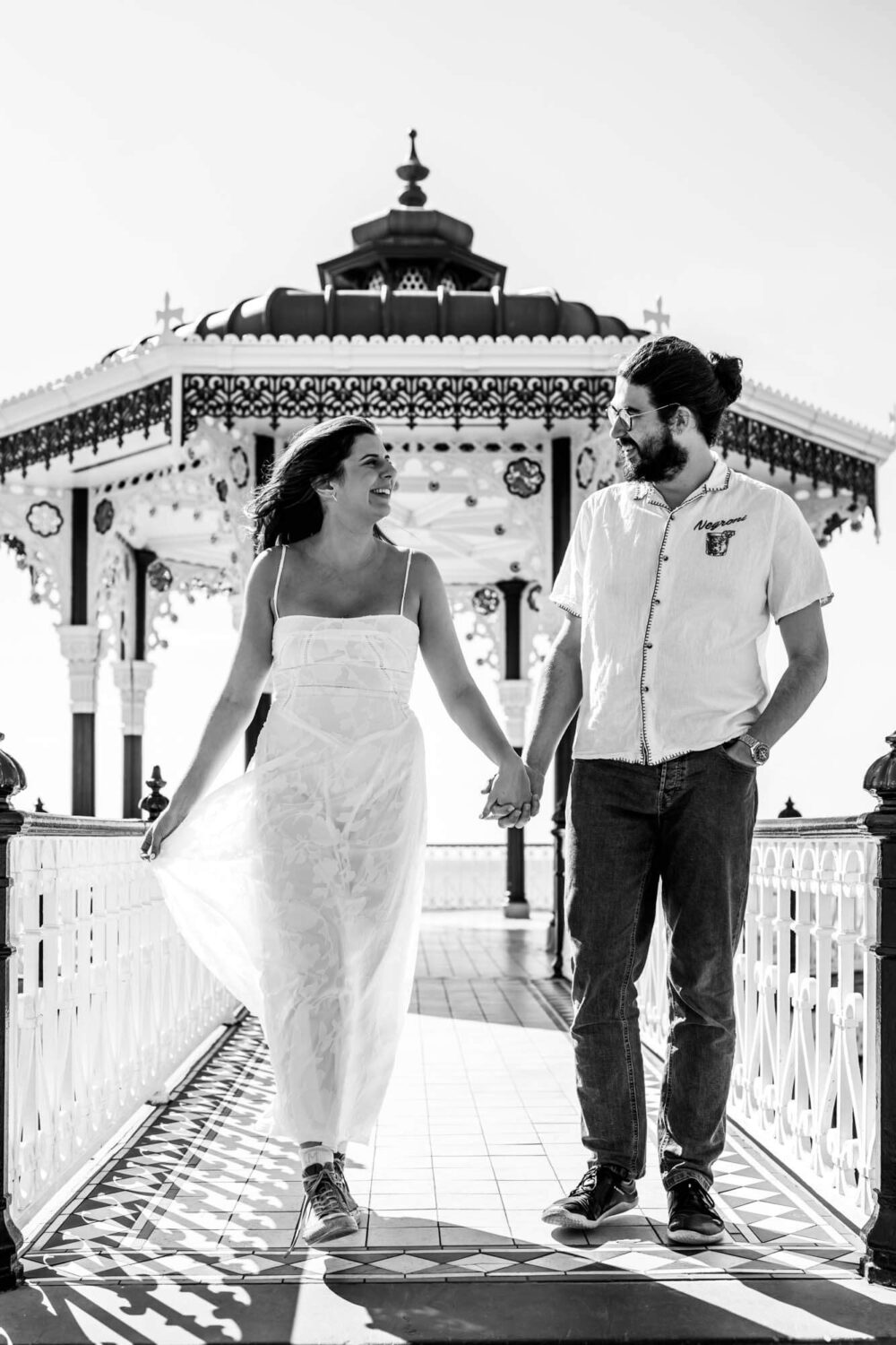 Couple holding hands walking off Brighton bandstand Brighton wedding.