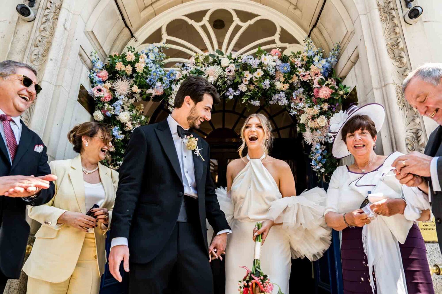 bride and groom walking out of registry office with parents with side and pure joy on their faces