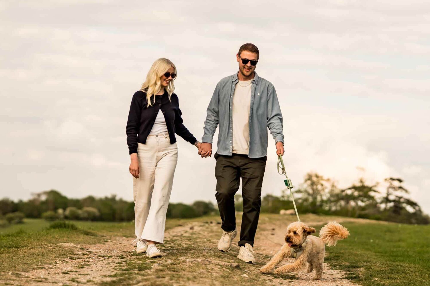 woman and man holding hands walking dog