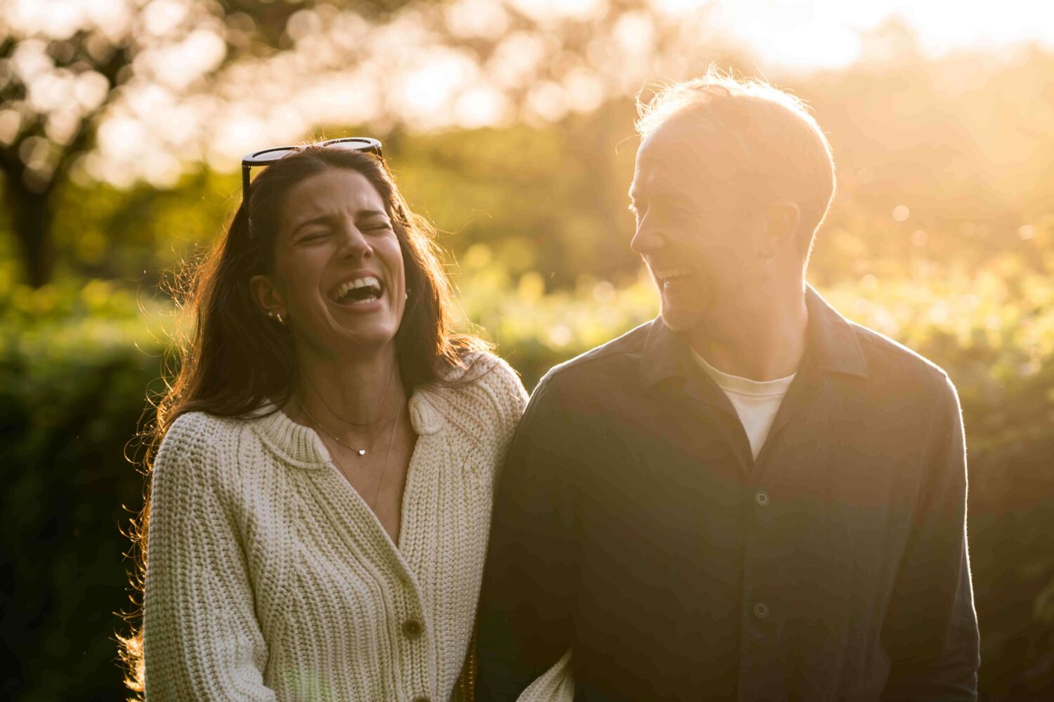 female walking along laughing with her partner in evening sunlight